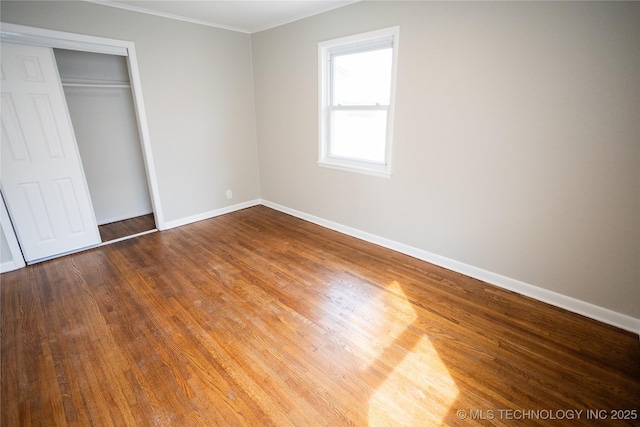 5760 E 29th St, Tulsa, OK 74114 - unfurnished bedroom featuring a closet, crown molding, baseboards, and wood finished floors