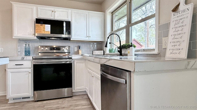 1721 S 114th E Ave, Tulsa, OK 74128 - kitchen featuring white cabinets, light countertops, tasteful backsplash, and appliances with stainless steel finishes