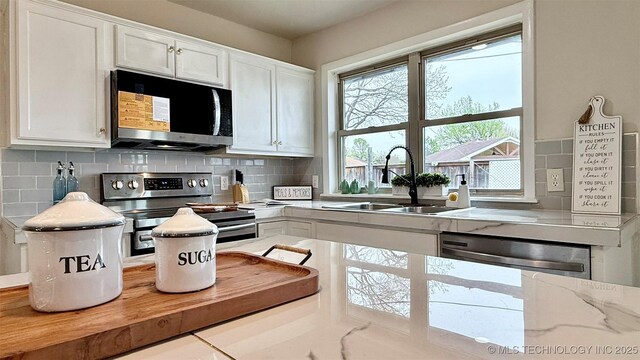 1721 S 114th E Ave, Tulsa, OK 74128 - kitchen with backsplash, white cabinets, a sink, and stainless steel appliances