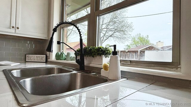 1721 S 114th E Ave, Tulsa, OK 74128 - room details with white cabinetry, decorative backsplash, and a sink