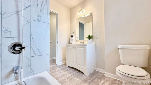 1721 S 114th E Ave, Tulsa, OK 74128 - full bathroom featuring washtub / shower combination, baseboards, wood finished floors, toilet, and vanity