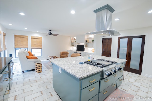 kitchen featuring stainless steel gas cooktop, a ceiling fan, a kitchen island, recessed lighting, and light stone countertops