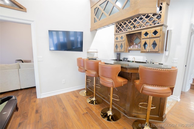 indoor wet bar featuring baseboards and light wood-style flooring