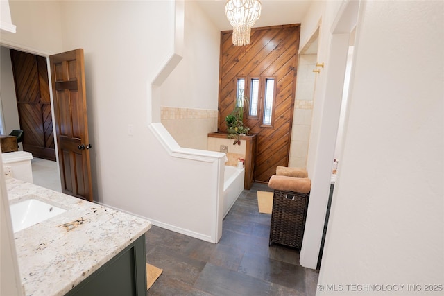 full bathroom featuring a chandelier, vanity, a bath, and wood walls