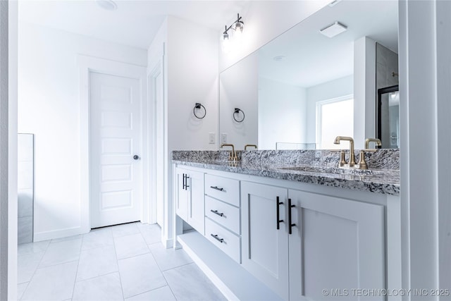 bathroom featuring baseboards, a sink, tile patterned floors, and double vanity