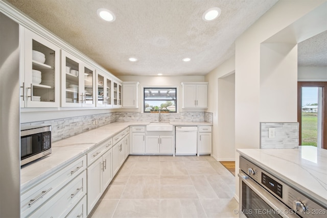 13542 N 155th E Ave, Collinsville, OK 74021 - kitchen with stainless steel appliances, decorative backsplash, plenty of natural light, a textured ceiling, and white cabinetry