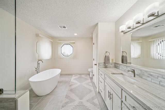 13542 N 155th E Ave, Collinsville, OK 74021 - full bathroom with vanity, a textured ceiling, a freestanding tub, tile patterned flooring, and recessed lighting