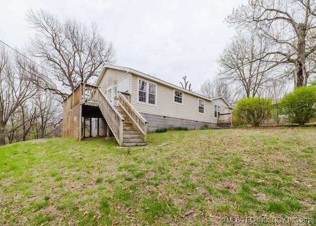 rear view of property featuring a yard, a wooden deck, and stairs