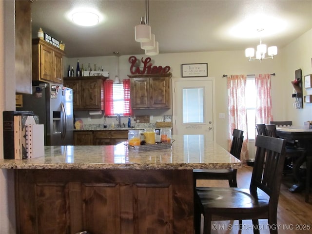 60 S Kaylee Rd, Calera, OK 74730 - kitchen with a kitchen bar, light stone countertops, a sink, a peninsula, and a notable chandelier
