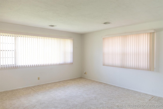 spare room with plenty of natural light, carpet floors, and visible vents