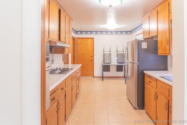 kitchen featuring baseboards, light countertops, under cabinet range hood, and appliances with stainless steel finishes