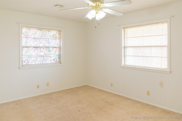 carpeted spare room with baseboards, ceiling fan, and visible vents