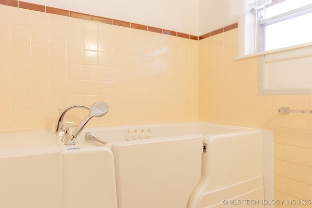 bathroom with tile walls and a garden tub
