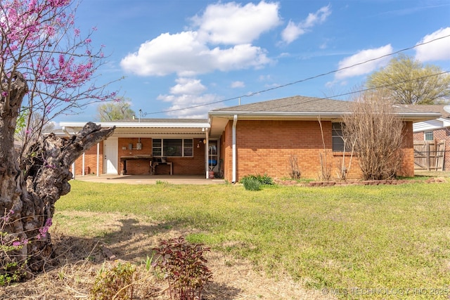 back of house with fence, a patio, brick siding, a yard, and a carport