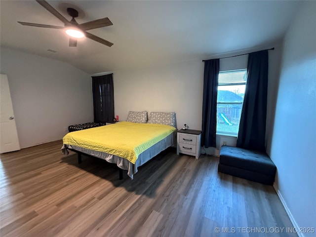 bedroom with baseboards, wood finished floors, vaulted ceiling, and a ceiling fan