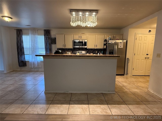kitchen with white cabinetry, stainless steel appliances, a chandelier, and light tile patterned floors