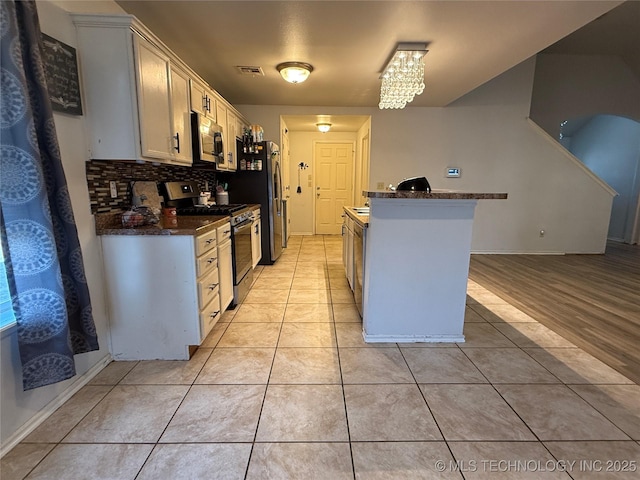 kitchen with light tile patterned floors, stainless steel appliances, tasteful backsplash, and visible vents