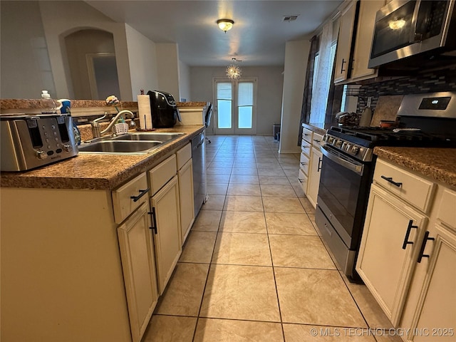 kitchen with decorative backsplash, a sink, light tile patterned flooring, visible vents, and appliances with stainless steel finishes