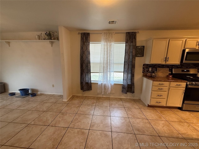 kitchen featuring tasteful backsplash, light tile patterned floors, stainless steel appliances, dark countertops, and visible vents