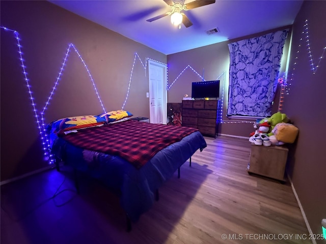 bedroom featuring baseboards, visible vents, wood finished floors, and a ceiling fan