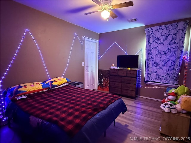 bedroom featuring ceiling fan, visible vents, and wood finished floors