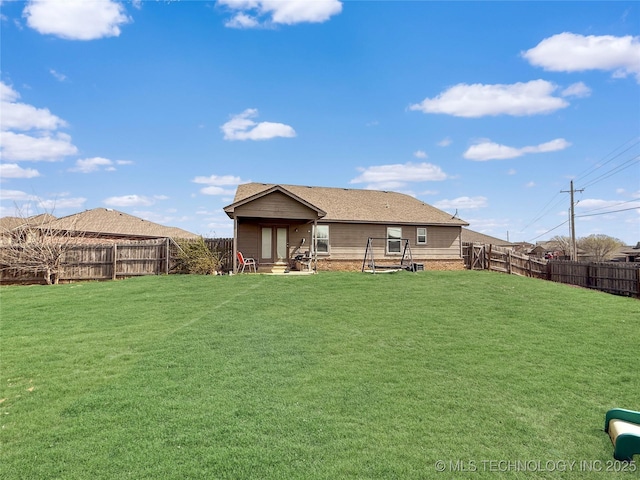 back of house with a lawn, a fenced backyard, entry steps, and roof with shingles