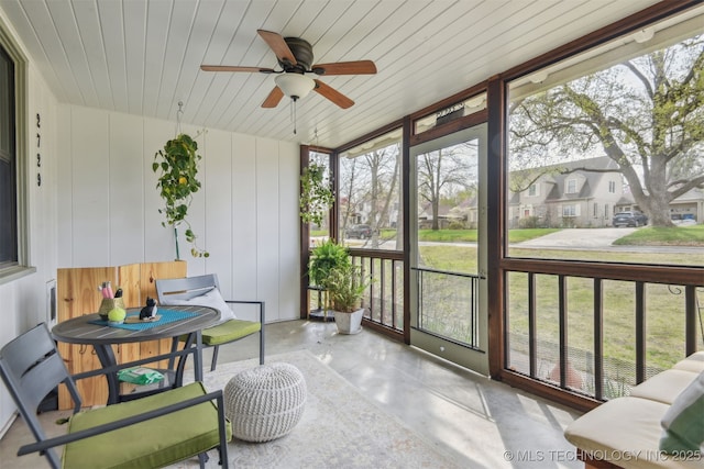 sunroom / solarium featuring a residential view, plenty of natural light, and ceiling fan