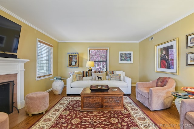 living area with visible vents, crown molding, and wood finished floors