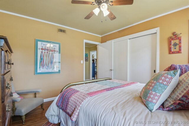 bedroom featuring wood finished floors, ornamental molding, a closet, and visible vents