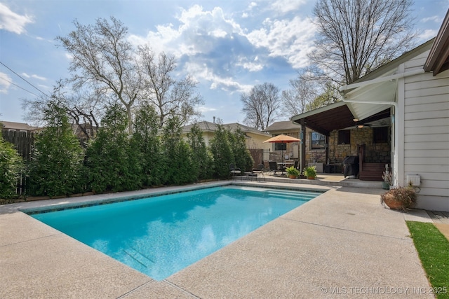 outdoor pool with fence and a patio