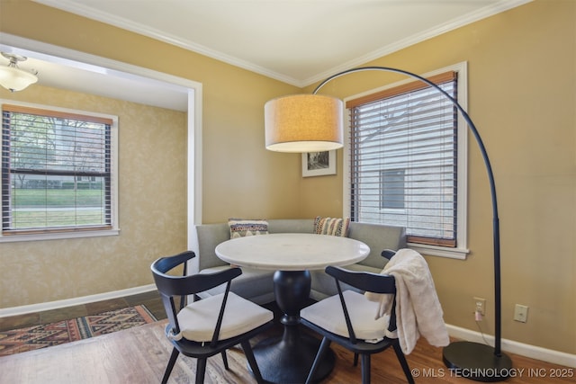 dining space featuring baseboards, wood finished floors, and crown molding