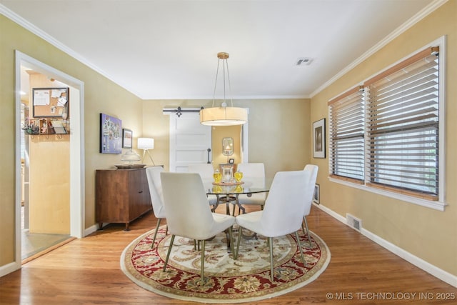 dining area with wood finished floors, ornamental molding, baseboards, and visible vents