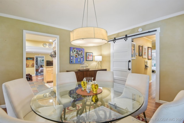 dining area featuring crown molding, baseboards, and a barn door