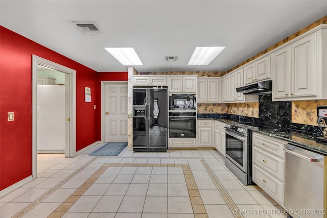 kitchen with under cabinet range hood, baseboards, light tile patterned flooring, visible vents, and black appliances