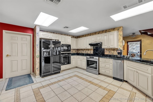kitchen with a sink, under cabinet range hood, visible vents, and black appliances