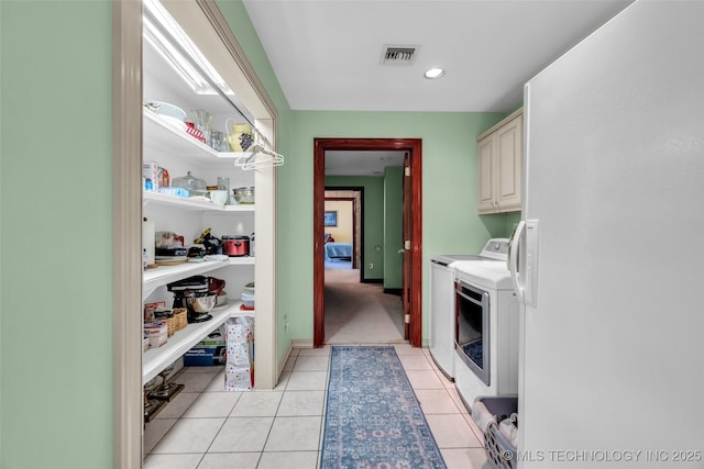 laundry area with independent washer and dryer, light tile patterned flooring, cabinet space, and visible vents