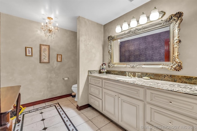 bathroom featuring baseboards, toilet, tile patterned floors, vanity, and a notable chandelier