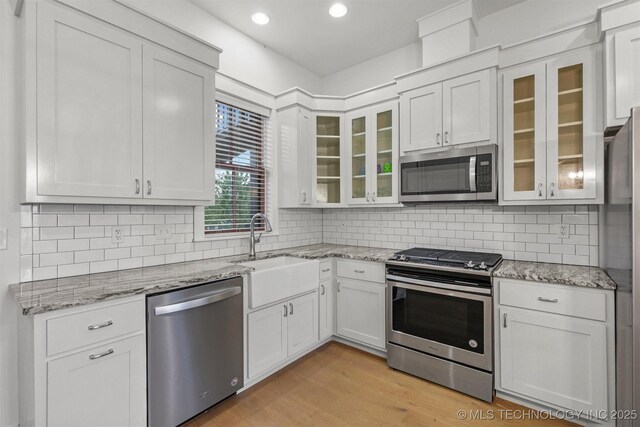 29 Water St Unit 4, Carlton Landing, OK 74432 - kitchen featuring light wood-style flooring, light stone countertops, appliances with stainless steel finishes, a sink, and backsplash