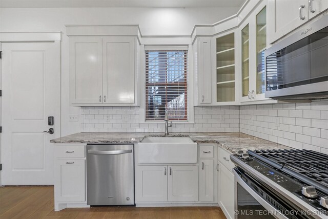 29 Water St Unit 4, Carlton Landing, OK 74432 - kitchen with light wood-type flooring, stainless steel appliances, a sink, light stone countertops, and glass insert cabinets