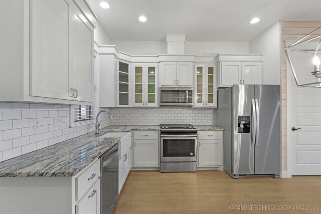 29 Water St Unit 4, Carlton Landing, OK 74432 - kitchen featuring tasteful backsplash, light wood-type flooring, a sink, light stone counters, and appliances with stainless steel finishes