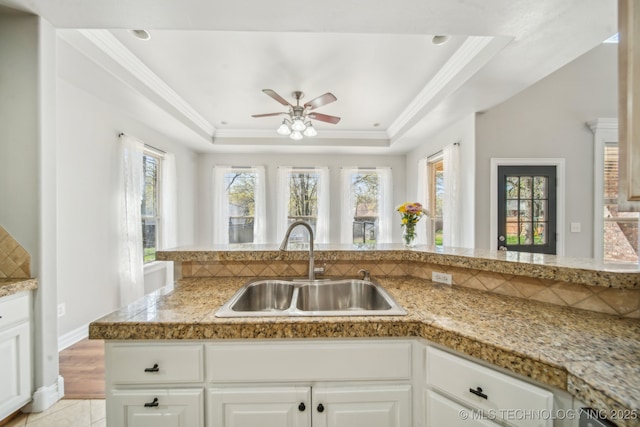 12916 E 181st St S, Bixby, OK 74008 - kitchen featuring a sink, tile counters, ceiling fan, a tray ceiling, and white cabinets