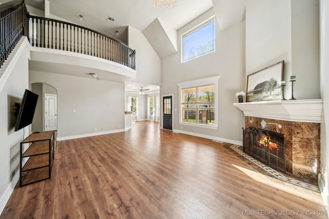 12916 E 181st St S, Bixby, OK 74008 - unfurnished living room with a high end fireplace, a towering ceiling, wood finished floors, arched walkways, and baseboards