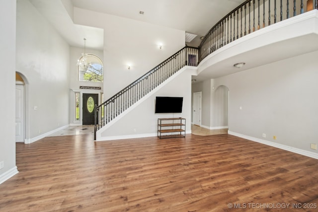 12916 E 181st St S, Bixby, OK 74008 - unfurnished living room with a towering ceiling, arched walkways, wood finished floors, and stairs