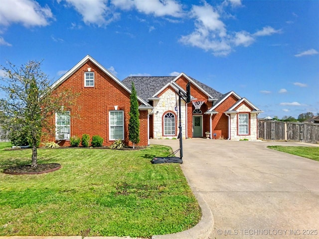 view of front of house featuring brick siding, concrete driveway, fence, and a front lawn