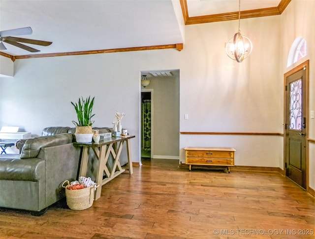 foyer entrance featuring crown molding, wood finished floors, baseboards, ceiling fan with notable chandelier, and visible vents