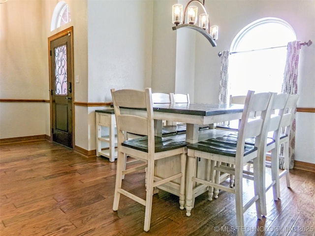 dining space with baseboards, a chandelier, and hardwood / wood-style flooring