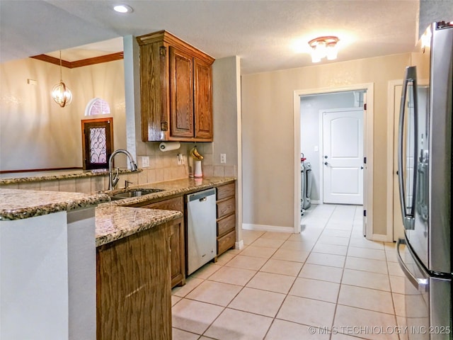 kitchen with light tile patterned floors, a sink, light stone counters, appliances with stainless steel finishes, and brown cabinetry