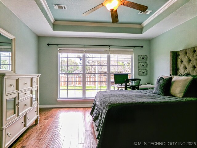 bedroom with visible vents, multiple windows, and a raised ceiling