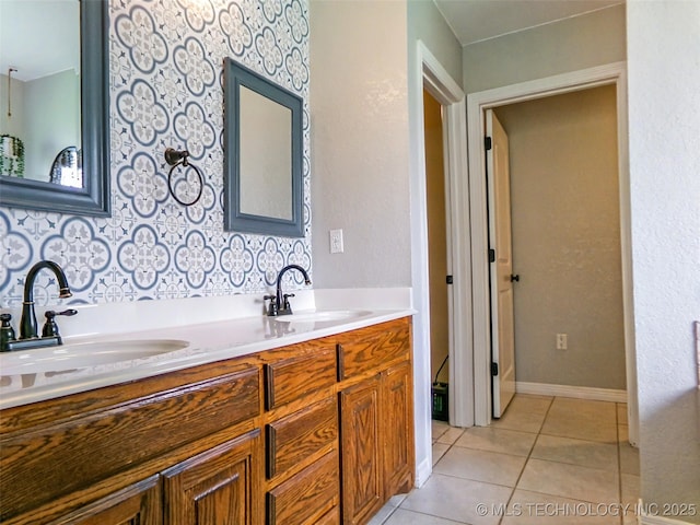 bathroom with tile patterned flooring, a sink, double vanity, and baseboards