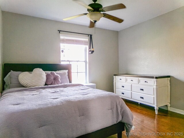bedroom with baseboards, ceiling fan, and dark wood finished floors